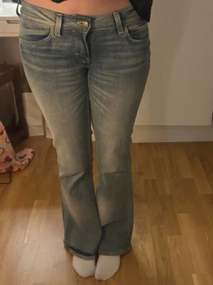 Bootcut jeans i ljusblå  - Säljer ett par snygga bootcut jeans i ljusblå denim med klassisk femficksdesign och låg midja. Jeansen har slitningar och en lätt tvättad look som ger en cool vintagekänsla. Perfekta för dig som gillar en avslappnad men trendig stil. Sälj pgr av ingen anledning 