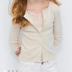 Beige ribbad kofta från Gina Tricot - Snygg beige ribbad kofta från Gina Tricot med rund halsringning och knäppning framtill. Koftan har långa ärmar och sitter figurnära. Perfekt att styla med ett linne under för en trendig look.