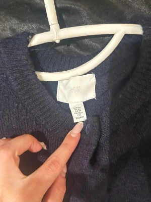 Mörkblå kofta/ cardigan från H&M, XS - Mysig mörkblå kofta från H&M med rund halsringning och knappar framtill. Långärmad modell i mjukt stickat material, perfekt att slänga över en t-shirt eller topp. Enkel och stilren design som passar till det mesta.