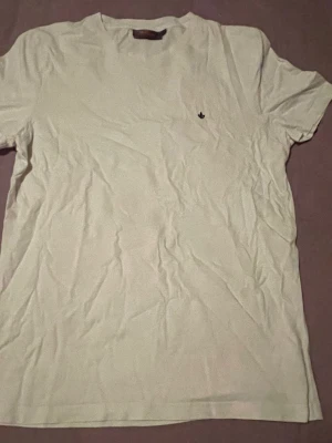 Vit t-shirt Från MORRIS - Säljer en enkel vit t-shirt med liten broderad logga på bröstet. Klassisk passform och rund halsringning. Perfekt basplagg till garderoben och lätt att matcha med allt. Tillverkad i mjuk bomull för skön känsla.
