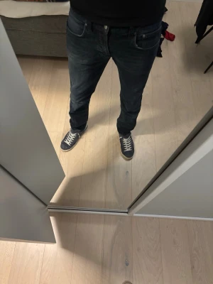 Mörkblå raka jeans - Säljer ett par mörkblå jeans med rak passform och klassisk femficksdesign. Jeansen har normal midja och är tillverkade i denim. Perfekta för en avslappnad och stilren look.