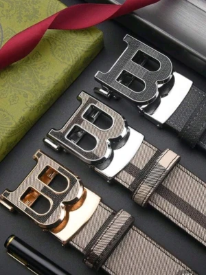 Burberry bälte - Snyggt randigt bälte med ett stort B-format spänne i metall. Finns i svart, silver och guldton. Bältet har en modern design med bred rem och tydliga ränder, perfekt för att lyfta din outfit med en cool detalj.