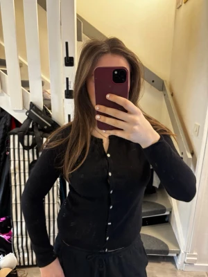 Svart kofta med pärlknappar - Stilren svart kofta med rund halsringning och dekorativa pärlknappar framtill. Långärmad och i mjukt, tunt material som passar perfekt till lager-på-lager. Enkel och klassisk design som funkar till det mesta. Pris kan diskuteras💖