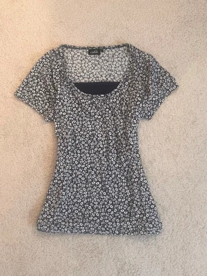 Blommig babydoll topp - Supersöt topp från Isolde med mörkblå botten och vitt blommönster. Modellen har rundad halsringning och korta ärmar. Materialet känns mjukt och lätt, bomull och viscose. Har inga tecken på användning. 