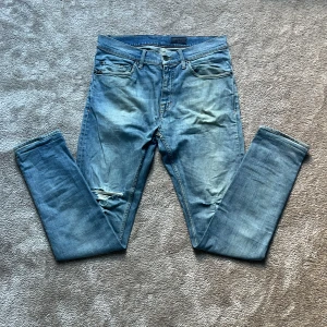  Jeans från Tiger of Sweden - Snygga ljusblå jeans från Tiger of Sweden med slitning vid knät. Jeansen har raka ben och normal passform, tillverkade i mjukt bomullsjeansmaterial. Storleken är W29 och L32. Priset kan diskuteras.
