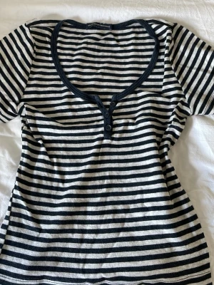 Brandy Melville tröja - En kortärmad gullig randig tröja från Brandy Melville🫶Har söta knappar vid bröstet. Ser inga defekter men är använd. 