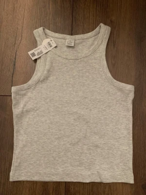 Ljusgrå ribbad linnetopp  - Säljer en ljusgrå ribbad linnetopp från Lindex med breda axelband. Helt oanvänd med prislappen kvar.💕