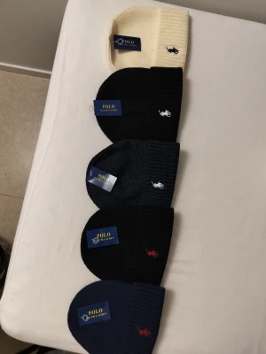 Polo Ralph Lauren mössa i flera färger en för 175 - Snygga ribbstickade mössor från Polo Ralph Lauren i färgerna cremevit, svart och marinblå. Klassisk design med broderad logga framtill i kontrastfärg. Perfekt accessoar för att hålla värmen och lyfta din stil. 175 per st.