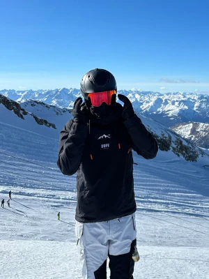 Skidjacka - Säljer en svart skidjacka från Dope med vit logga och bergmotiv på bröstet. Jackan har huva, dragkedjor med orange detaljer och en sportig passform. Perfekt för skidåkning eller andra vinteraktiviteter.