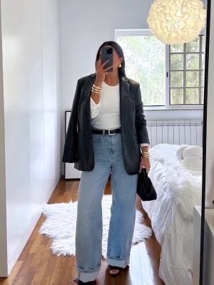 Svart kavaj i skinnimitation - Stilren svart kavaj med två knappar och klassisk krage, tillverkad i skinnimitation. Kavajen har raka axlar, långa ärmar och fickor framtill.                   stor i strl men passar till XS ( kanske S) 