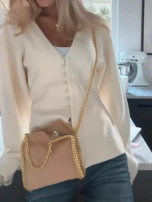 Beige handväska med guldkedja - Snygg krämvit kofta med v-ringning och dekorativa knappar framtill. Storlek S. Mycket bra skick.