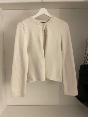 Vit stickad kofta - Snygg och enkel vit stickad kofta med rund halsringning och långa ärmar. Koftan har en rak passform och stängs med en knapp upptill. Köpt för 360kr. Är i storlek xs men passar även mig som brukar ha s.