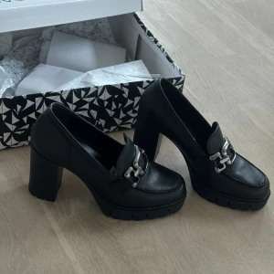 Tamaris Loafer Pumps med platå nypris 1400kr - Nypris: 1400kr Klackhöjd: 9,5cm Nyskick, använda 1 gång. Loafers med klack i äkta skinn, lika bekväma som snygga. Måste tyvärr säljas då passformen inte blir helt rätt även med inlägg. Nybehandlade med skokräm.  Slutsålda både på Scorett och Håkansso