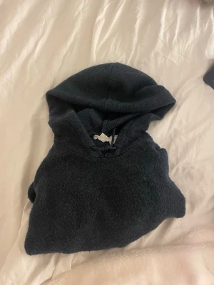 Mörkgrå stickad hoodie - Mysig mörkgrå stickad hoodie med huva och lång ärm. Perfekt för att chilla hemma eller dra på sig när det är lite kyligt. Materialet är mjukt och ger en avslappnad vibe. Inga synliga loggor eller tryck.