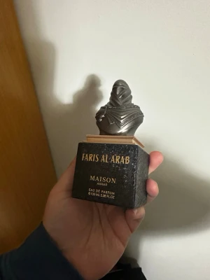Faris Al Arab parfym Maison Asrar (Clive Christian Blonde Amber) - Unik parfymflaska från Maison Asrar, Faris Al Arab. Flaskan är svart med gulddetaljer och har ett lock i form av en staty med arabisk inspiration. Eau de Parfum, 100 ml. Flaskan har en lyxig och elegant design som sticker ut i parfymhyllan. 90% kvar; OBS! Saknar original förpackning!