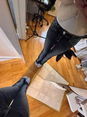 Mörkblå bootcut jeans med brodyr - Säljer ett par mörkblå bootcut jeans med vita kontrastsömmar och snygg brodyr på bakfickan. Jeansen har låg midja och klassisk femficksdesign. Perfekta för dig som gillar en avslappnad men ändå trendig stil.