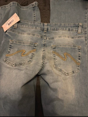 Bootcut jeans med låg midja från Nelly - Bootcut jeans i ljusblå denim från Nelly med låg midja. Bakfickorna har dekorativa broderier i gult och vitt. Ny med prislapp, bara provade. Säljer då de var lite för långa för mig.   Jag är 159 och de är några cm för långa.  Köpte de för 699kr på Nelly. Skriva gärna innan du tänker köpa då de ligger uppe på Vinted också!🙈🤗