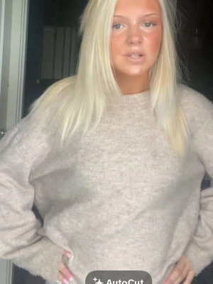 Beige stickad tröja med rund hals - Mysig beige stickad tröja med rund hals och långärmad design. Perfekt för lager-på-lager och enkel att matcha med jeans eller kjol. Tröjan har en loose passning och är tillverkad i stickat material.