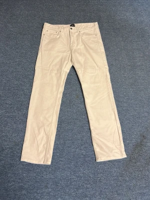 Beiga chinos från H&M Regular Fit - Snygga beiga chinos från H&M i modellen Regular Fit. Klassisk femficksdesign och raka ben. Tillverkade i ett mjukt bomullstyg som är skönt att bära. Perfekta för en clean och avslappnad stil.