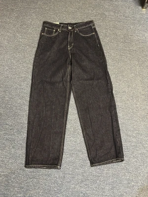 Loose fit jeans i mörk denim - Säljer ett par loose fit jeans i mörkblå denim med kontrasterande vita sömmar. Jeansen har klassisk femficksdesign och raka ben. Perfekt för dig som gillar en avslappnad och trendig look.