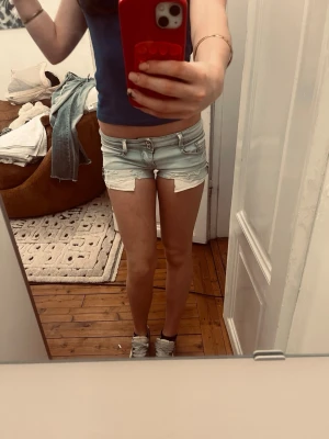 Skitsnygga Ljusblå jeansshorts  - Säljer ett par ljusblå denimshorts med råa, fransiga kanter och femficksdesign. Shortsen har låg midja och Perfekta inför sommaren