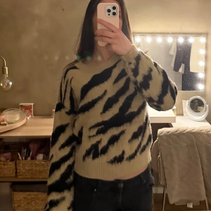 Beige och svart zebramönstrad tröja - Stickad tröja i beige med svart zebramönster. Tröjan är mjuk och jättebekväm. Säljer den då den aldrig har använts och är även lite för liten.