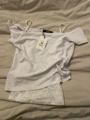 Vit spets topp - Säljer en topp i stockholmsstil med spetströja från Shein XS och en vit, kort topp med off shoulder-motiv M från Bikbok. Det finns en smuts- och dammfläck på sidan som kan tas bort från tvätten eller med diskmedel! De är nya.