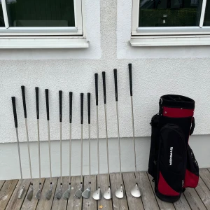 Golfbag Striker svart och röd - Golfbag från Striker i svart och rött golfsetet innehåller 5,6,7,8,9,pw,sw,3 hybrid,1 driver, 1 putter lite repor men de syns inte så mkt. Klubborna är gjorda av grafit och är väldigt lättspeade