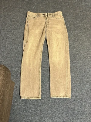 Gråa raka jeans från Jack&Jones - Säljer ett par gråa raka jeans från Jack&Jones med klassisk femficksdesign och knappgylf. Perfekta för dig som gillar en clean och avslappnad stil.