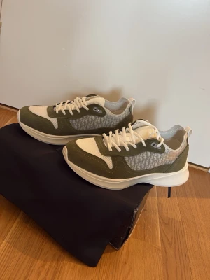 Gröna och vita sneakers  - Stilrena sneakers i grönt och vitt med meshpaneler och mockadetaljer. Skorna har vita snören, tjock vit sula och en modern, sportig look. Perfekta för dig som gillar trendiga och bekväma sneakers med snygga detaljer.