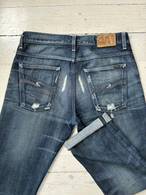Nudie jeans selvedge Lab Joe - Otroligt feta Nudie jeans i modellen Lab Joe. De är selvage i riktig gott skick, en lös tråd på läderlappen baktill är det enda att anmärka på och möjligen att texten på lappen där modellen står är har fadeats bort. Storlek 34/34.Jeansen har använts lite men aldrig tvättats av mig men köpte dem på vinted och har antagligen tvättats innan. Börjat få lite heelbite och hade nog mått bra av en tvätt om inte allt för lång tid, men tänker att det är upp till nästa ägare att bestämma :) Skriv gärna vid
