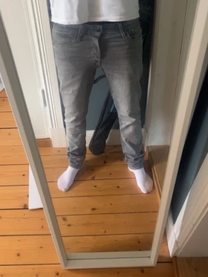 Grå slim fit jeans  - Snygga grå slim fit jeans med klassisk femficksdesign och låg midja. Jeansen har en smal passform och är tillverkade i ett stretchigt denimtyg som ger en bekväm känsla. Perfekta för en avslappnad och trendig look.