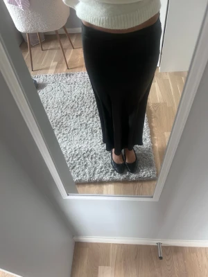 Svart långkjol i satin - Säljer en elegant svart långkjol med lätt glansig finish och figurnära passning. 
