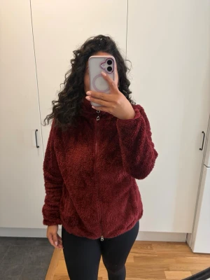 Vinröd teddyjacka med dragkedja - Mysig vinröd teddyjacka med hög krage och dragkedja framtill. Jackan har en fluffig och mjuk textur, långa ärmar och en avslappnad passform. Perfekt för kalla dagar när du vill vara både varm och snygg. Inköpt på Hööks☺️