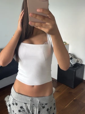 Vit croppad topp - Snygg vit croppad topp med fyrkantig ringning och ribbad struktur. Toppen har korta ärmar och sitter tight mot kroppen. Lite nopprig annars inga defekter