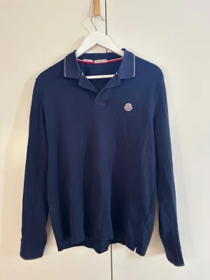 Moncler långarmad piké  - Säljer denna långärmade pike från moncler, perfekt inför sommaren. Använd fåtal gånger, skick 9/10. Säljer då den blivit för liten för mig. Storlek L men sitter som M. Nypris 3600kr, mitt pris 1200kr. Skriv vid frågor och funderingar!