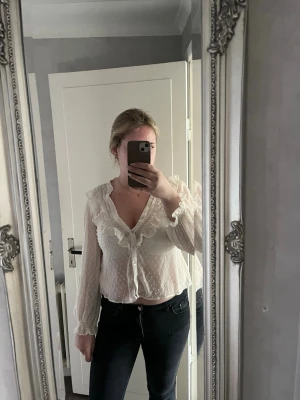Vit volangblus med prickigt mönster - Söt vit blus med volanger längs v-ringningen och knappar framtill från Zara i storlek M💗