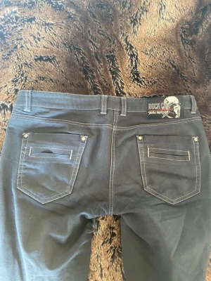 Svarta lågmidjade jeans - Snygga svarta lågmidjade 2000s jeans från Rock Chef. Köpta begagnat och säljs då jag har växt ut dem. Strl 29/32 men skulle säga att dem är en liten M. Jag kan knäppa dem men dem är väldigt tajta och jag har strl M/36 i byxor. Mått rakt över se bilder. 💕💕