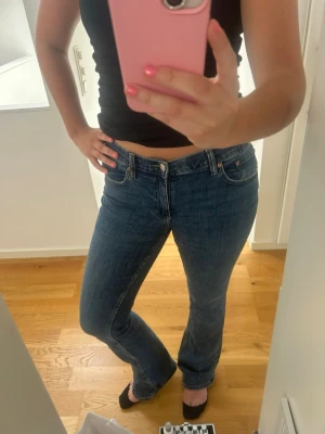 Blå raka jeans med klassisk passform - Säljer ett par blå jeans med rak passform och normal midja. Jeansen har klassiska fem fickor och stängs med knapp och dragkedja. Perfekta för dig som gillar en tidlös och enkel stil. Materialet är denim och färgen är mediumblå.