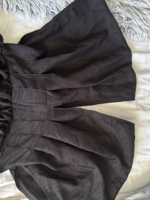 Svarta vida linneshorts - Säljer ett par svarta shorts med hög midja och riktigt vida ben. Shortsen är gjorda i ett luftigt linnematerial och har en elastisk midja som ger en skön och avslappnad passform. Perfekta för varma dagar och en chill stil.