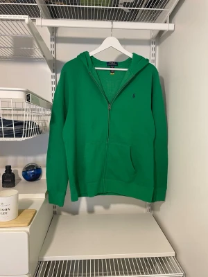 Grön hoodie från Polo Ralph Lauren - Säljer denna Ralph Lauren zip hoodien, i ett väldigt bra skick och är knappt använd. Barnstorlek XL vilket motsvarar herr S. Kontakta vid funderingar och kom gärna med prisförslag!