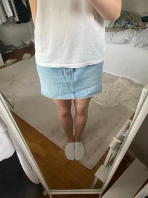 Jeanskjol - Säljer denna ljusblåa jeanskjol från Levis köpt för 800 kr i storlek 30. Den är knappt använd och har inga defekter. 