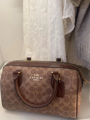 Brun Satchel bag coach  - Snygg handväska från Coach! Väskan har två handtag, dragkedja upptill och en tag med Coach-logga. Köpt i coach butik i USA sommaren 2025, använd några enstaka gånger. Nyskick!! Säljer den då jag använder den för lite :( 