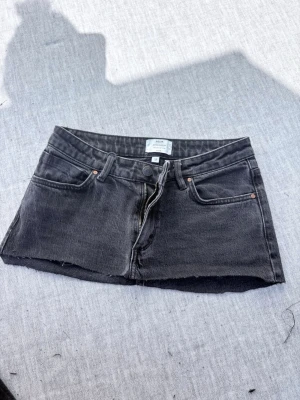 Svart jeanskjol från Neuw - Kort svart jeanskjol från Neuw med rå kant nertill och klassiska fem fickor. Kjolen har dragkedja och knapp framtill samt detaljer i kopparfärg. Det var innan ett par jeans som jag sytt om till en kjol
