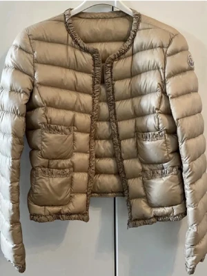 Moncler jacka - Säljer min fina Moncler jacka då jag inte använt den på länge nu, fint skick och fin varm beige färg. Kemtvättats en gång så skicket håller i. Storlek 2 vilket motsvarar S men tycker denna modellen är mindre i storleken så skulle absolut säga att det mer är som en XS. Skriv gärna för frågor eller fler bilder, svarar så fort jag kan💗står det inte ”såld” så finns den kvar. Självklart äkta, kan skanna in bevis om det önskas.
