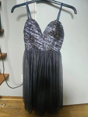 Svart paljettklänning med tyllkjol Gina Tricot - Snygg svart kortklänning från Gina Tricot med glittrig paljettöverdel och tunna axelband. Kjolen är gjord i flera lager tyll som ger ett fluffigt intryck. Perfekt för dig som vill sticka ut med extra glitter och volym. Aldrig använd.