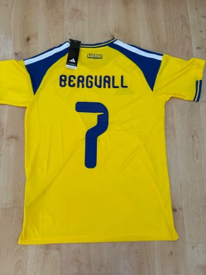 Bergvall #7 – Sverige Hemma (storlek M) - Bergvall #7-tryck. Sverige Hemma (gul). Storlek M. Helt ny och aldrig använd. Skickas snabbt 🚚💨  Mått (M): Halvt bröstmått 53 cm • Längd 74 cm • Ärmbredd 23 cm • Axelbredd 44 cm • Ärmlängd 40 cm • Manschett 19 cm.  🔥 Fan Edition – normal passform. 🇸🇪 Sverige landslag.  📩 Frågor eller prisförslag? Skicka gärna ett meddelande! 🛍 Bundle-rabatt upp till 20% 💰 📦 Skickas samma eller nästa dag 🌟