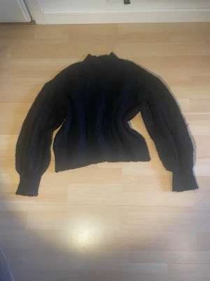 Stickad tröja - Tröjan är köpt här på Plick men jag använde aldrig den. Säljer för samma pris som jag köpte den 🥰Mysig mörkgrå stickad tröja med polokrage och kabelstickat mönster. Tröjan har långa, något pösiga ärmar och ribbade muddar vid ärmslut och nederkant. Perfekt för kalla dagar och enkel att styla till olika outfits.