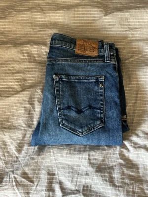Blå jeans från Replay - Säljer ett par klassiska blå jeans från Replay med fem fickor och snygga slitningar. Jeansen har en mörk tvätt, raka ben och detaljerade sömmar på bakfickan. Tillverkade i bomull med en skön passform. Perfekta för en avslappnad stil. Storleken är w29 l30. Bara att höra av er vid frågor eller funderingar 😌