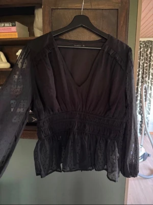 Svart blus från Boohoo - Snygg svart blus från Boohoo med prickiga långärmar och v-ringning.  Storlek 44